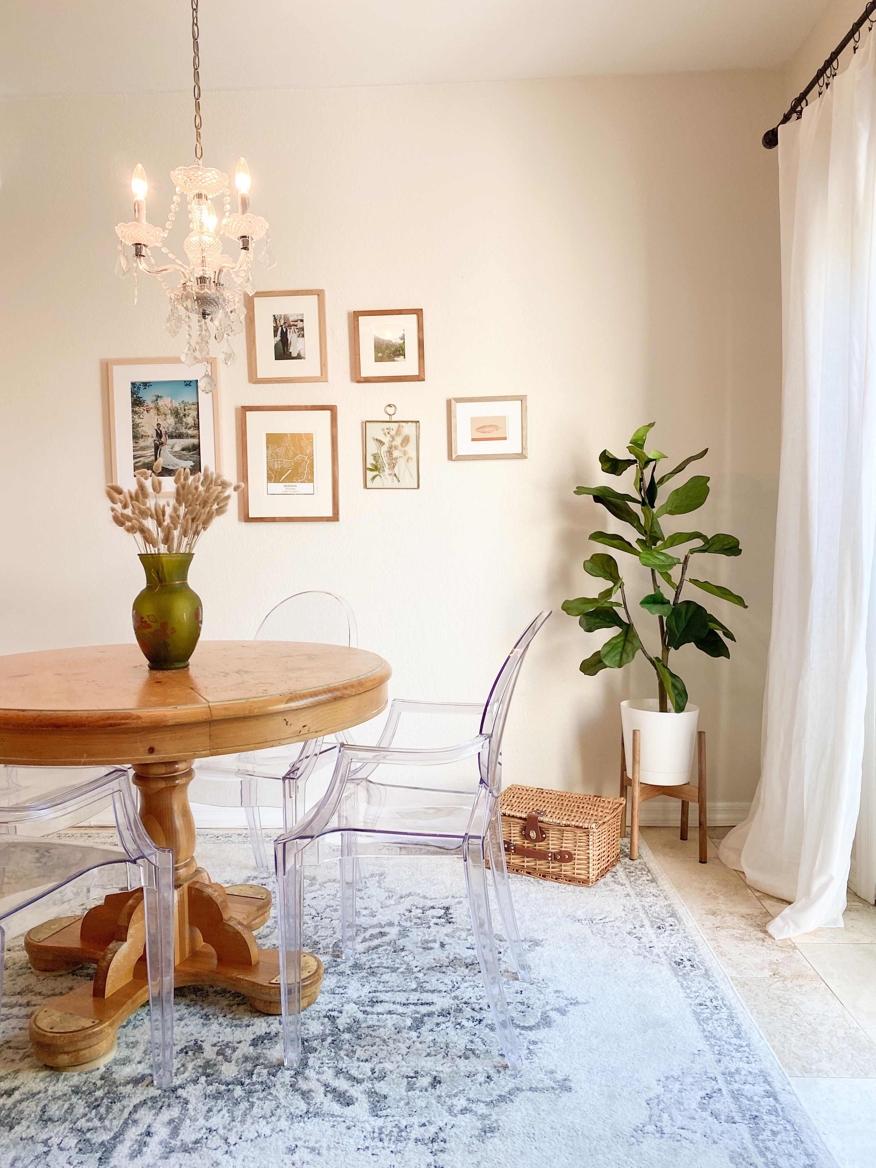natural boho dining room. round oak table. faux tree. gallery wall. area rug. clear chairs. modern boho decor.