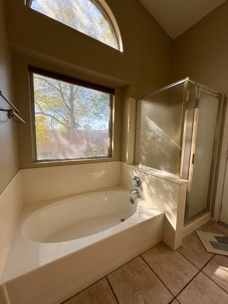 tub-and-shower-before-remodel 90s builder grade primary bathroom before remodel. soaking tub with glass shower and pony wall